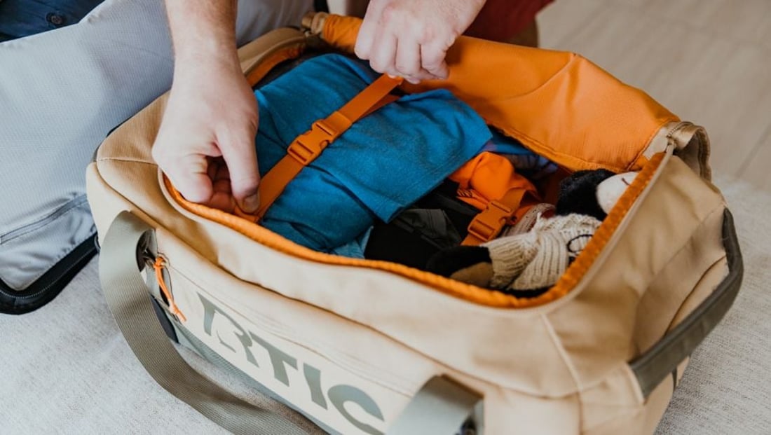 Tan RTIC Road trip rolling duffle bag is packed with clothes