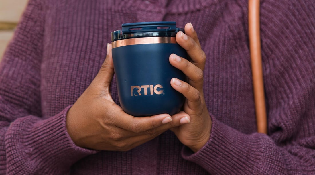 Someone holding a navy blue RTIC Daybreak Coffee Cup.