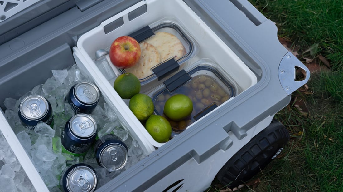 RTIC 72QT Ultra-Light wheeled cooler shown in use with dividers and dry goods basket, filled with ice, food, and drinks.
