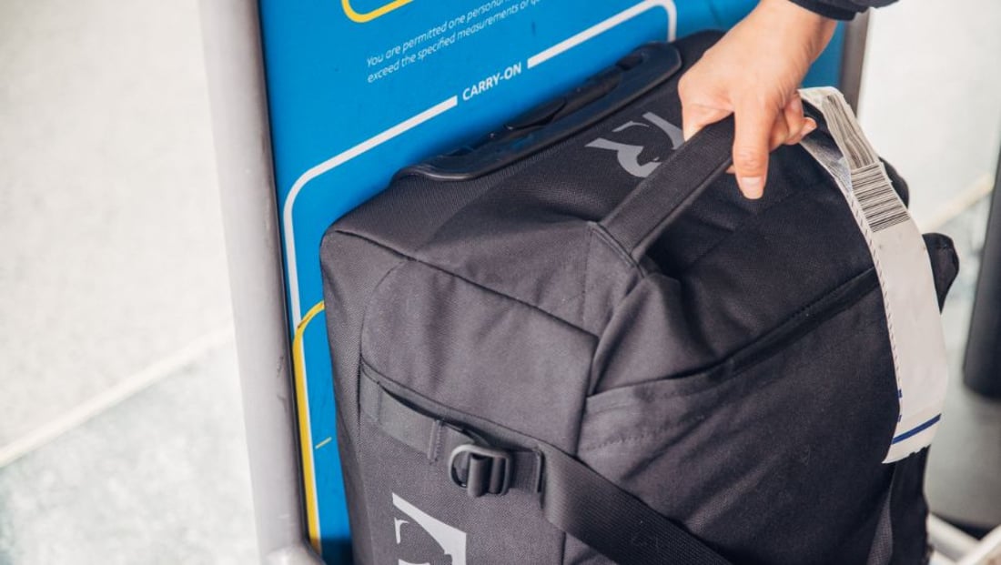 Medium Black RTIC Road Trip rolling duffle fits in an airline overhead bin, showing compliance with carry-on size requirements.