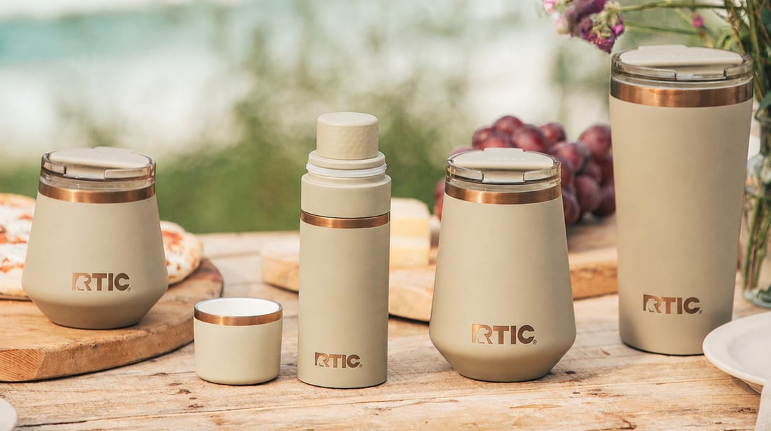 A group of tan-colored RTIC Happy Hour Collection barware at the beach.