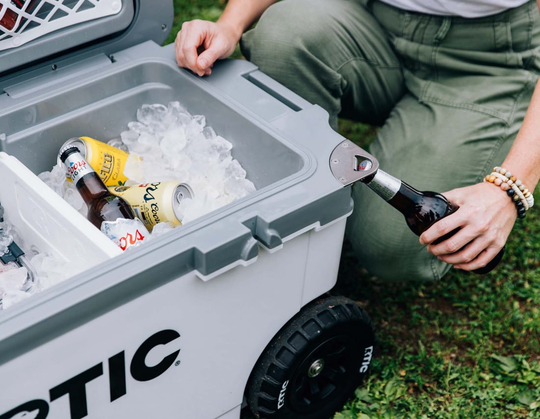 White 72QT Ultra-light Wheeled Cooler with built in bottle opener being used