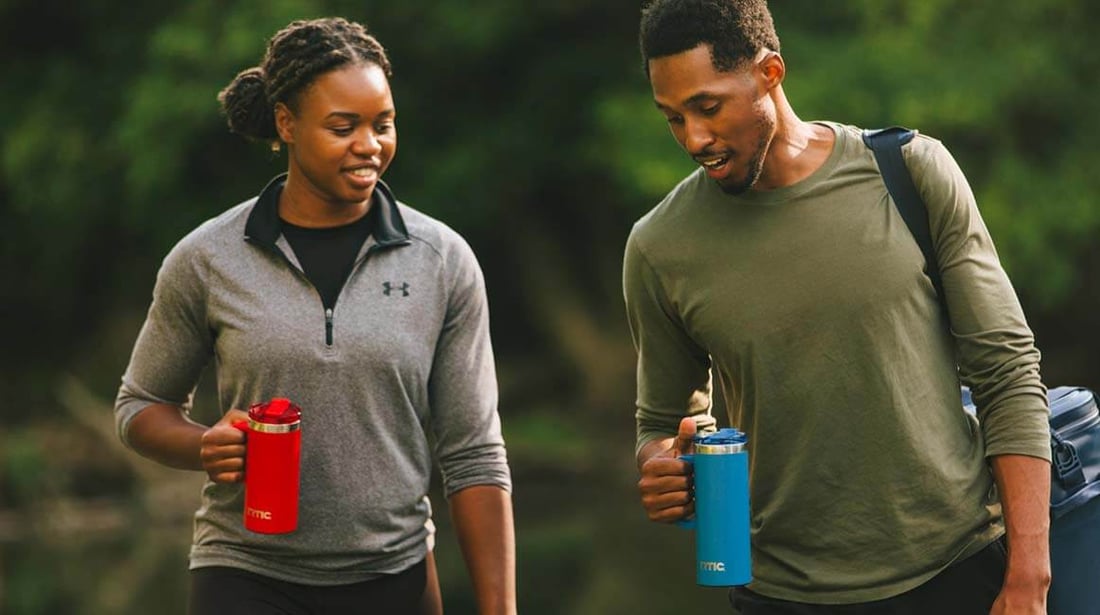 Man and woman walking outside holding their RTIC road trip travel mugs