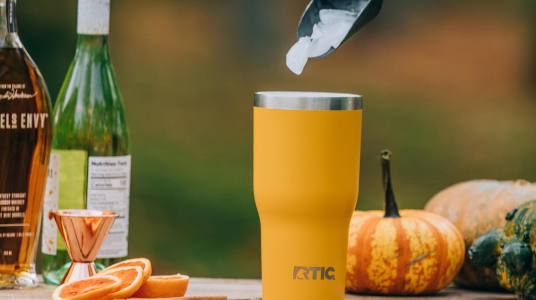 Ice being scooped into a yellow RTIC Essential Tumbler for a fall-themed cocktail.