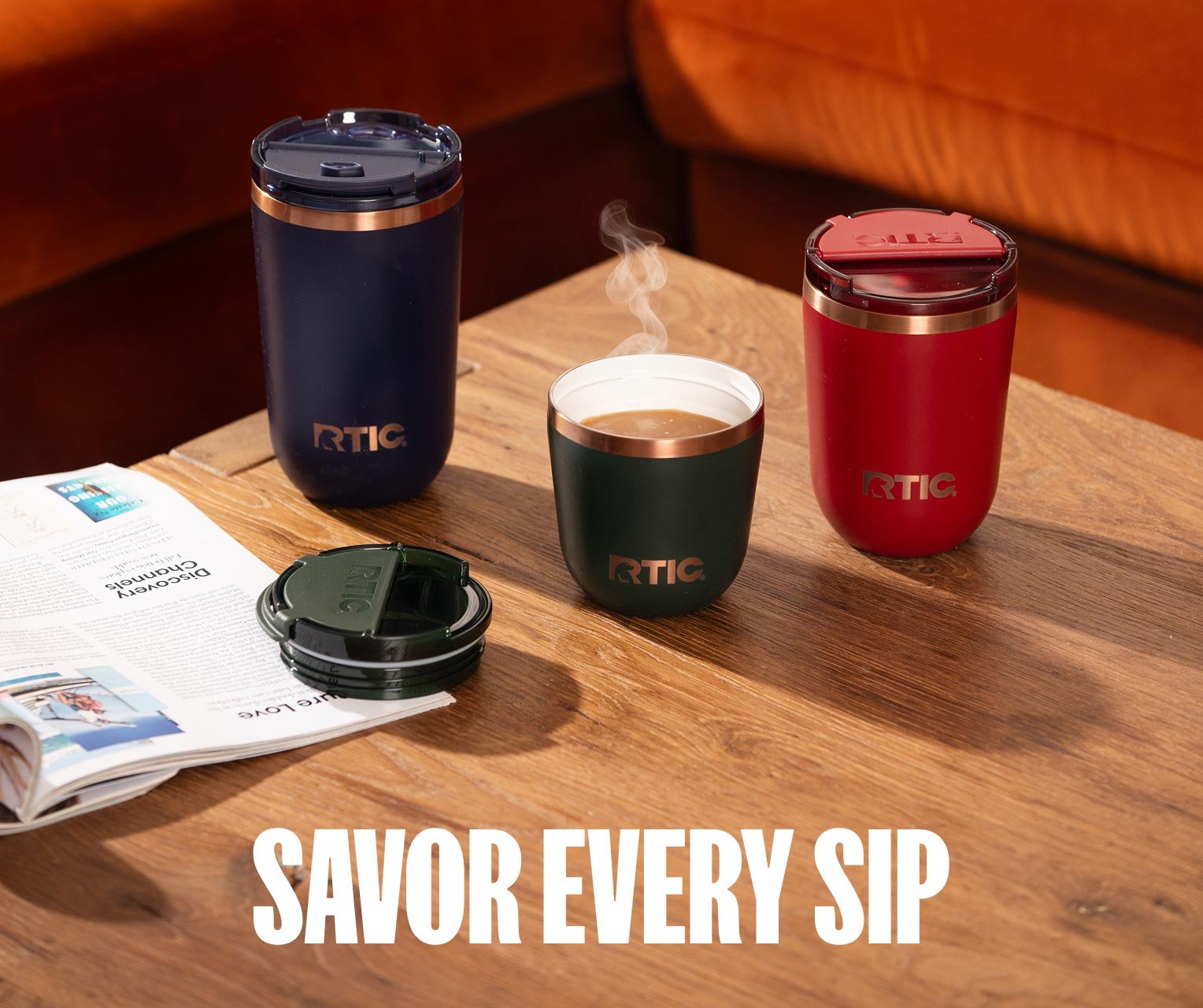 A group of RTIC Daybreak Coffee Cups in red, navy blue, and dark green sitting on a coffee table.