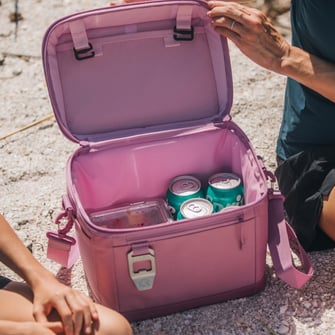 A close-up on an open purple RTIC fabric soft cooler with drinks inside.