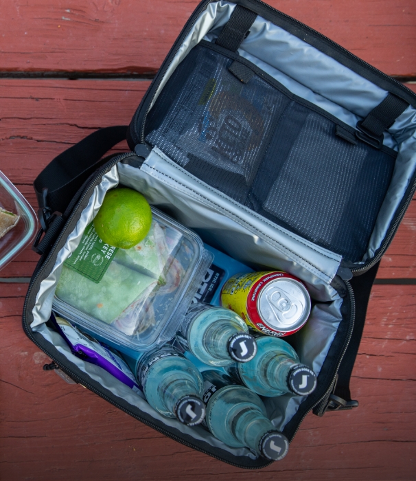 RTIC fabric soft cooler packed with ice packs, food, and drinks on a picnic table.