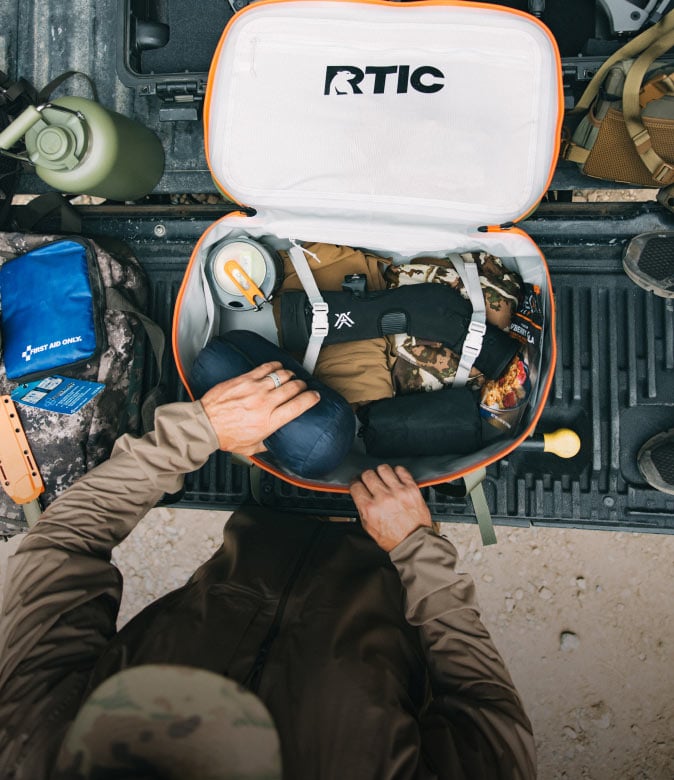 RTIC backpack packed with outdoor gear and supplies in a truck bed.
