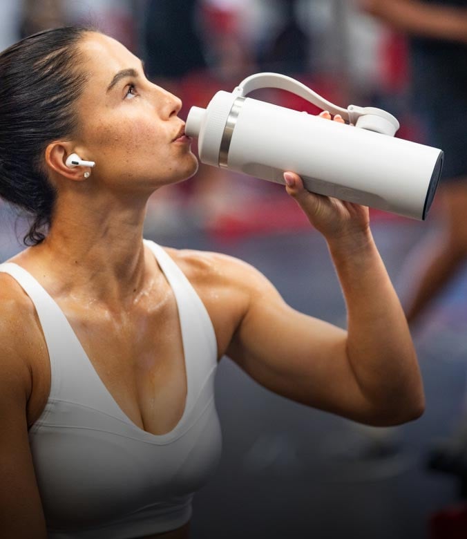 Woman drinking from a cool grey bottle during a workout.