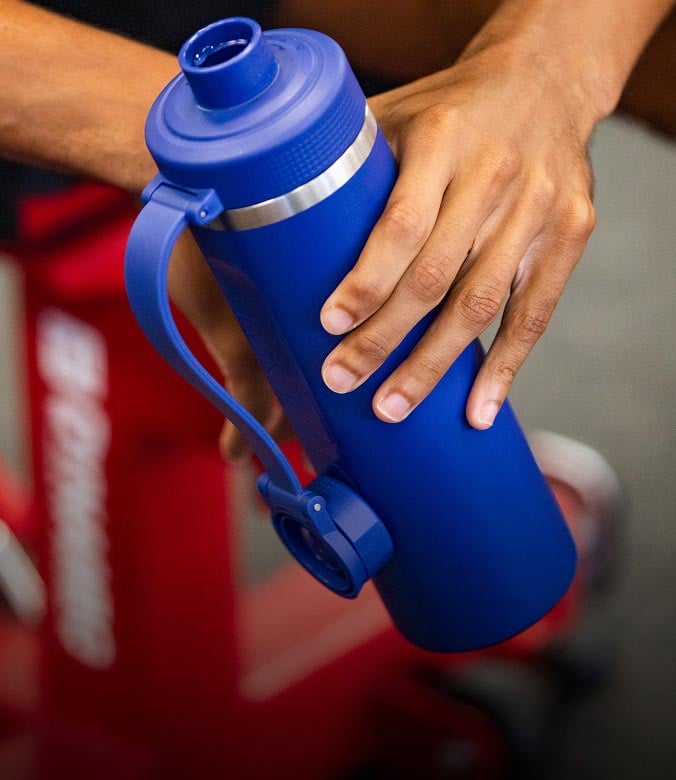 Person holding a blue bottle with a screw-top lid.