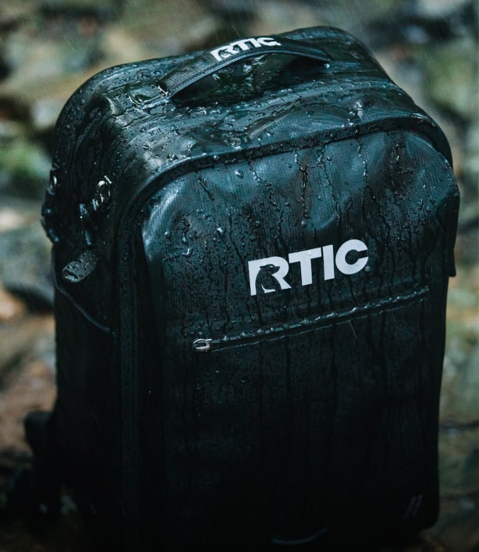 A close-up on a black RTIC Ultra-Dry Backpack in the rain.