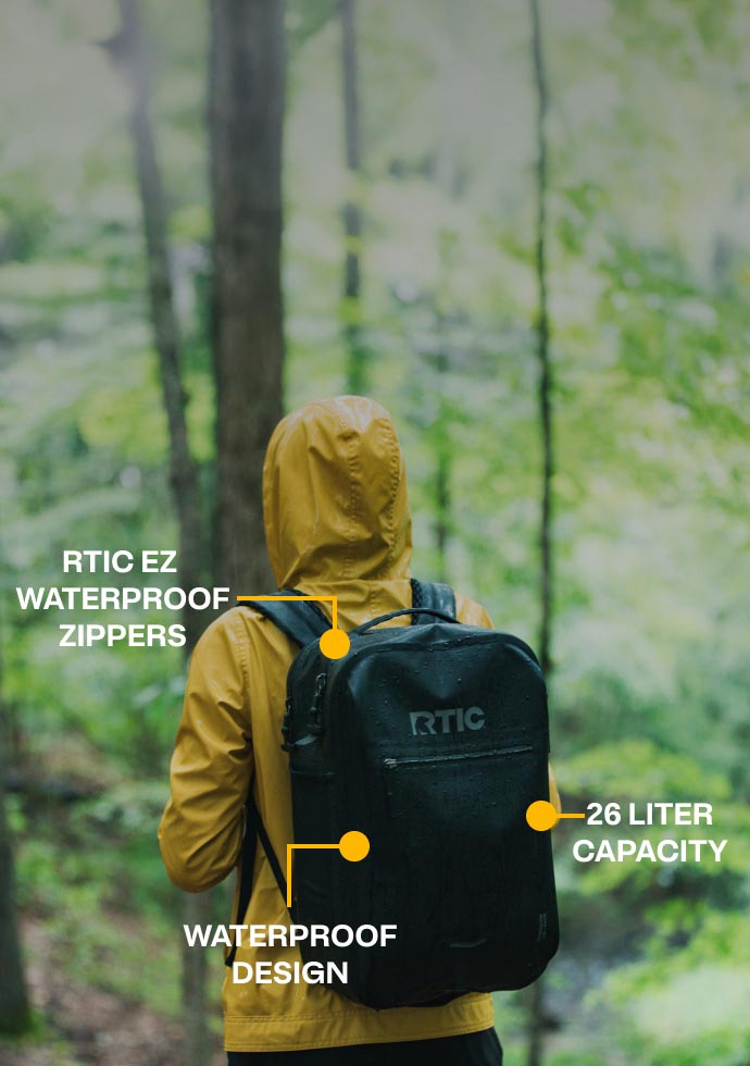 A person walking through the woods, wearing an RTIC Ultra-Dry backpack.