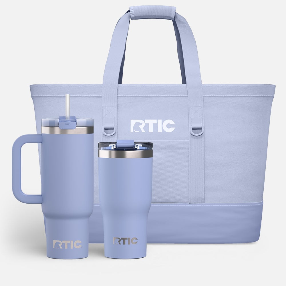 Pastel purple RTIC tote with handles, shown with two matching insulated tumblers in front on a white background.