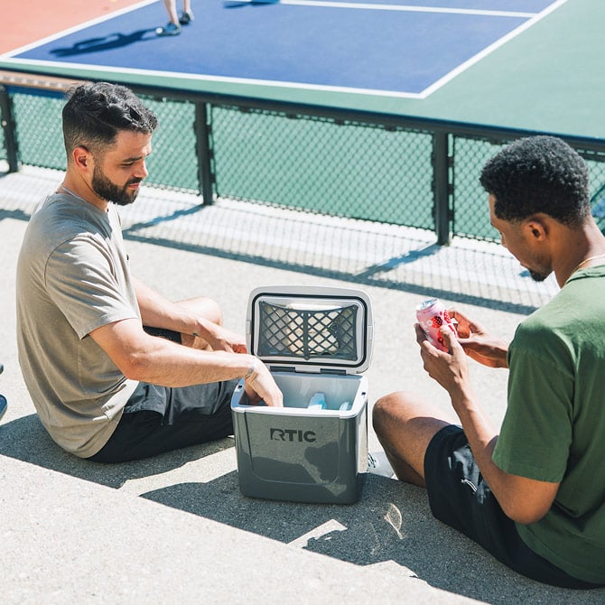 Two friends taking soda cans out of a Road Trip Personal Cooler.
