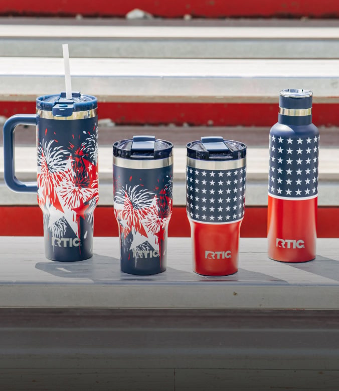 RTIC insulated tumblers, mug, and water bottle with patriotic red, white, and blue designs on bleachers.