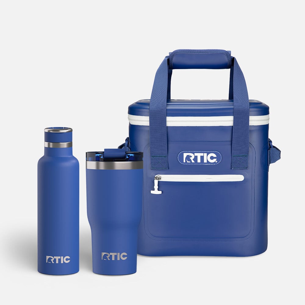 Cobalt blue RTIC soft cooler with front zipper pocket, paired with a matching insulated bottle and tumbler on a white background.