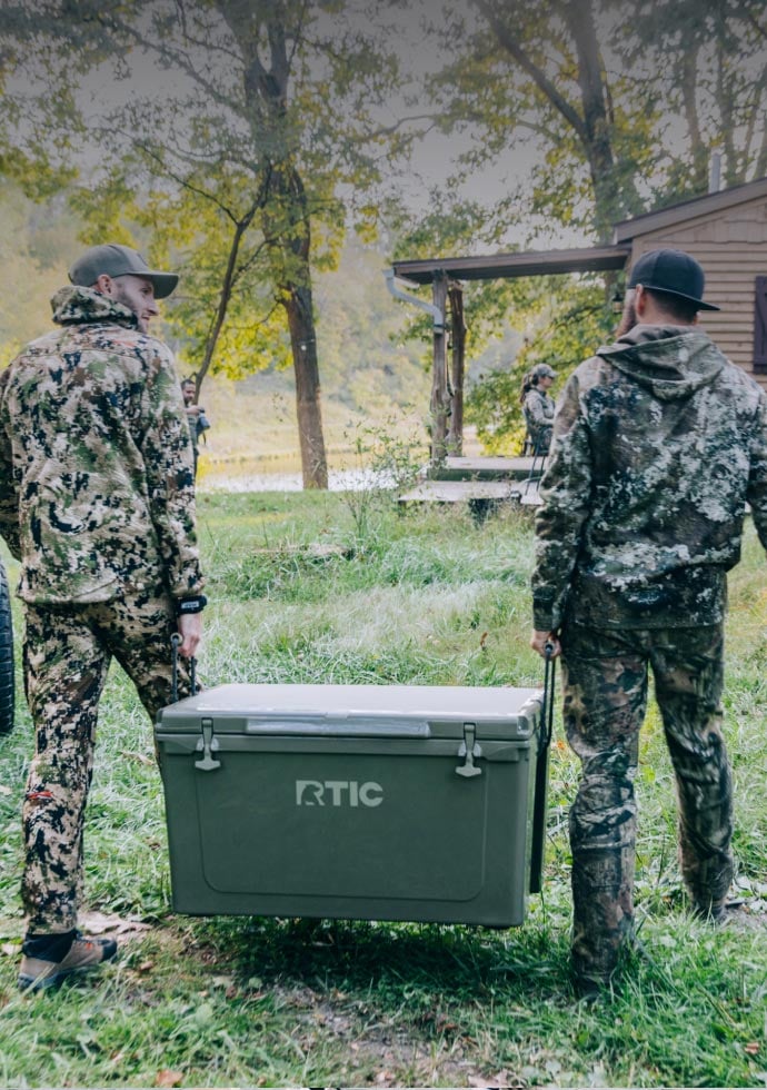 two men in camo carrying olive RTIC Cooler