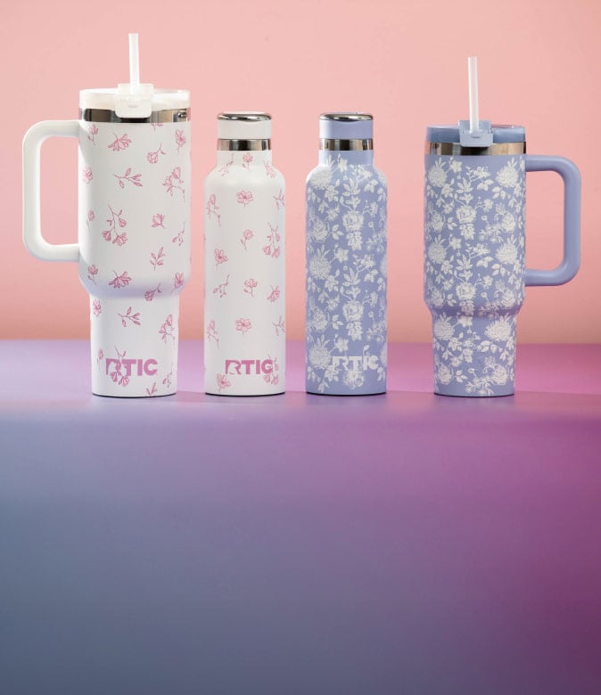 Assorted RTIC drinkware featuring pink and white floral patterns, including slim bottles and large handled cups with straws.