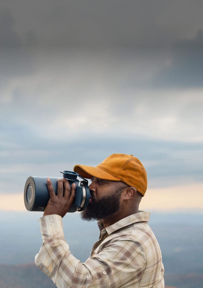 Man drinking out of Navy outback jug with cloudy background.
