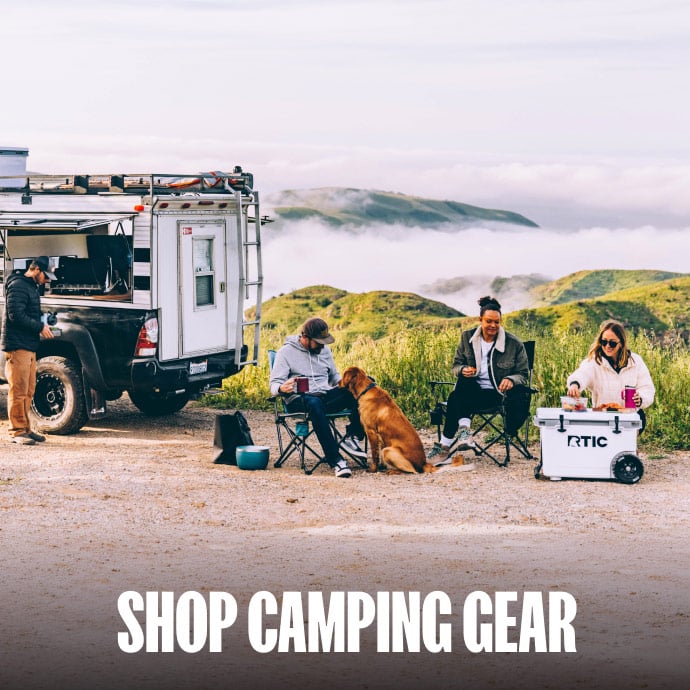 A group of friends car camping on a coastal bluff with a white RTIC wheeled cooler.