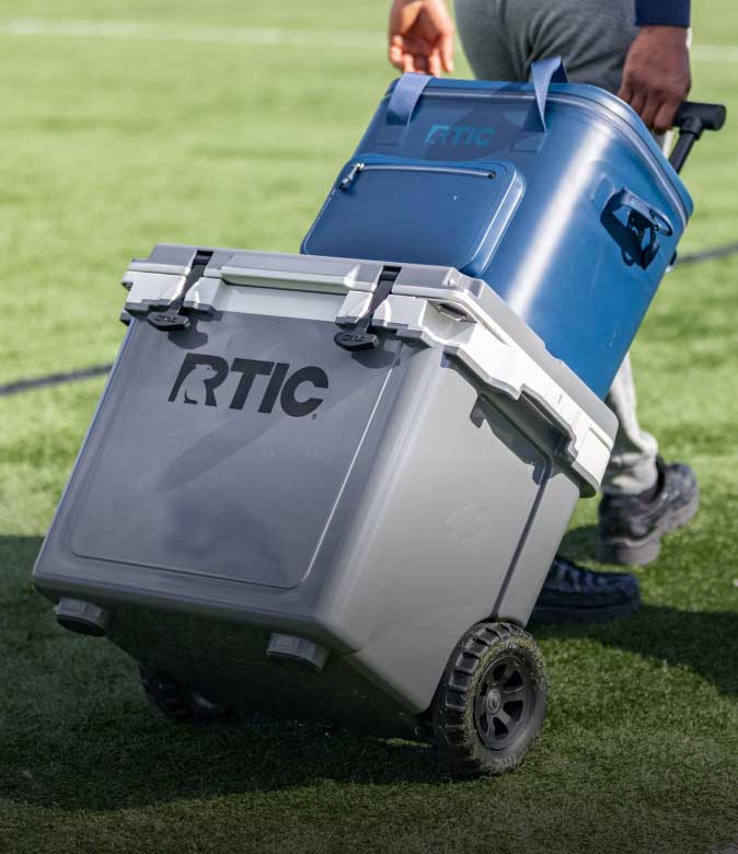 A grey RTIC 42 QT Ultra-Light Wheeled Cooler with a navy soft cooler stacked on top of it.