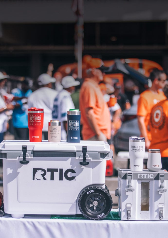 RTIC 52-qt wheeled cooler and RTIC drinkware on a tailgate table