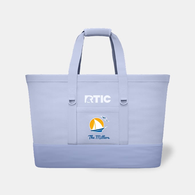 A periwinkle RTIC Insulated Tote Bag personalized with "The Millers" and a sailboat on it on a light grey background.