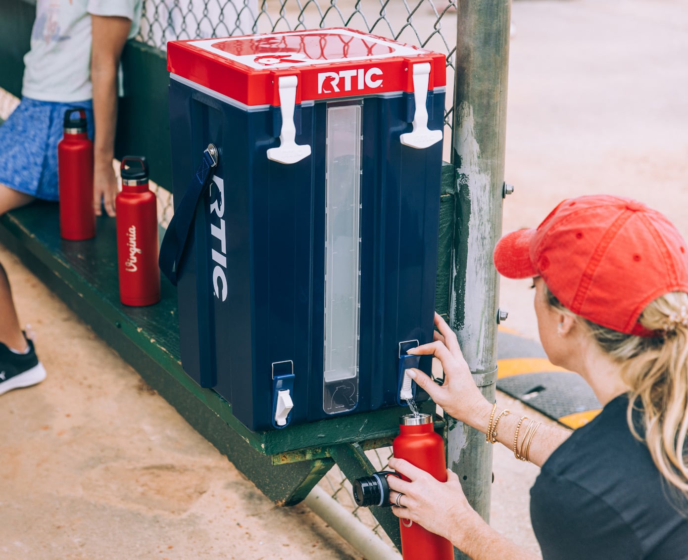 A woman getting water from a patriot RTIC Halftime Cooler.