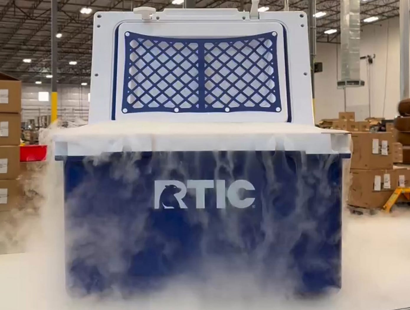 A blue RTIC hard cooler with dry ice gases rolling out of it.
