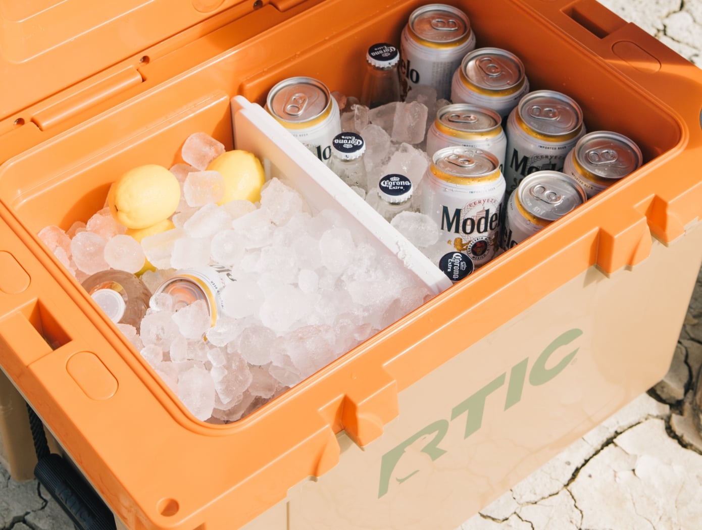 Orange and tan RTIC hard cooler filled with ice and drinks.